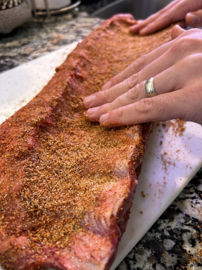 rubbing spice rub into meat of ribs with hands