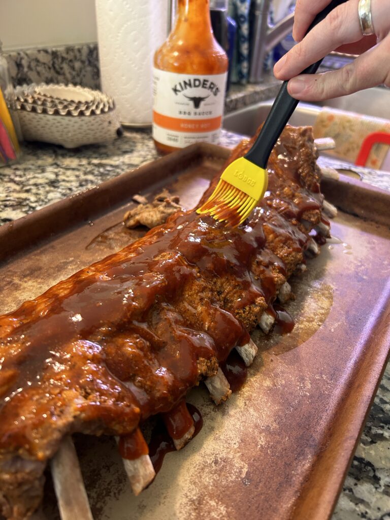 using a brush to evenly coat ribs with BBQ sauce