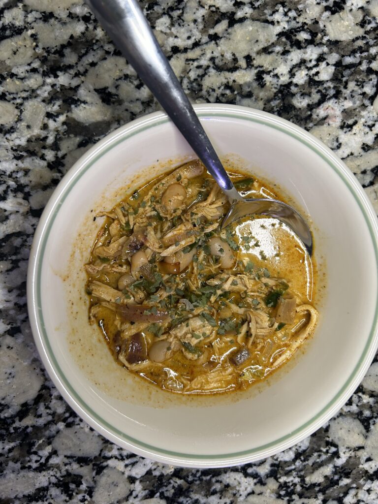 A bowl of white turkey chili topped with cilantro
