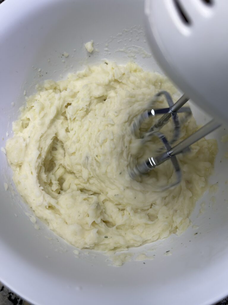 hand mixer mixing together potatoes, butter, and milk to make mashed potatoes
