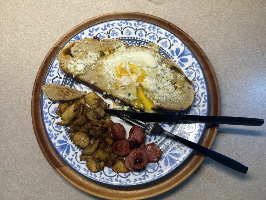 egg in toast with smoked sausage and fried potatoes on plate