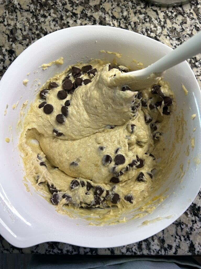 spoon mixing chocolate chips into banana bread batter