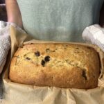 person holding homemade chocolate chip banana bread in bread pan