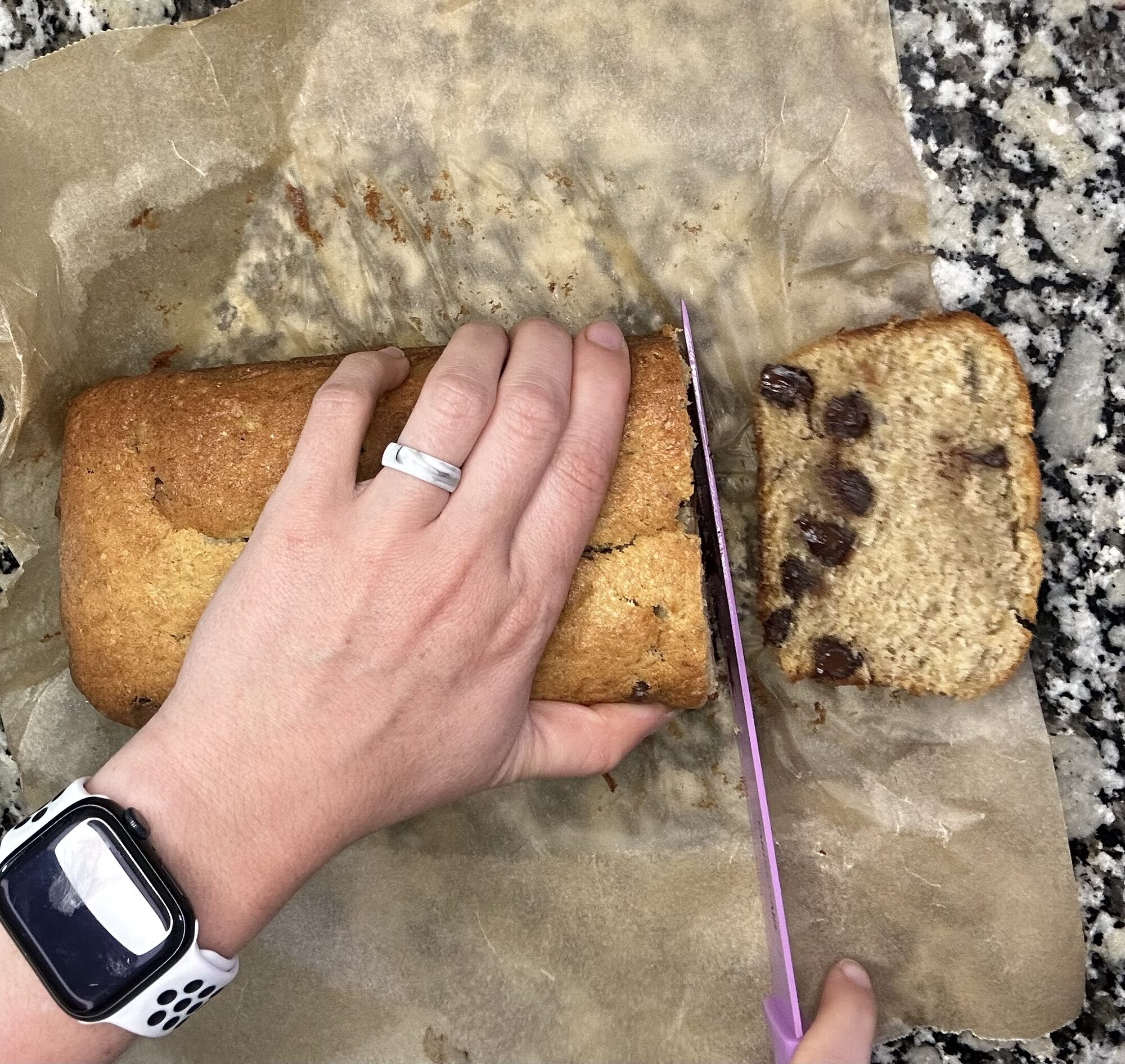 person slicing homemade chocolate chip banana bread