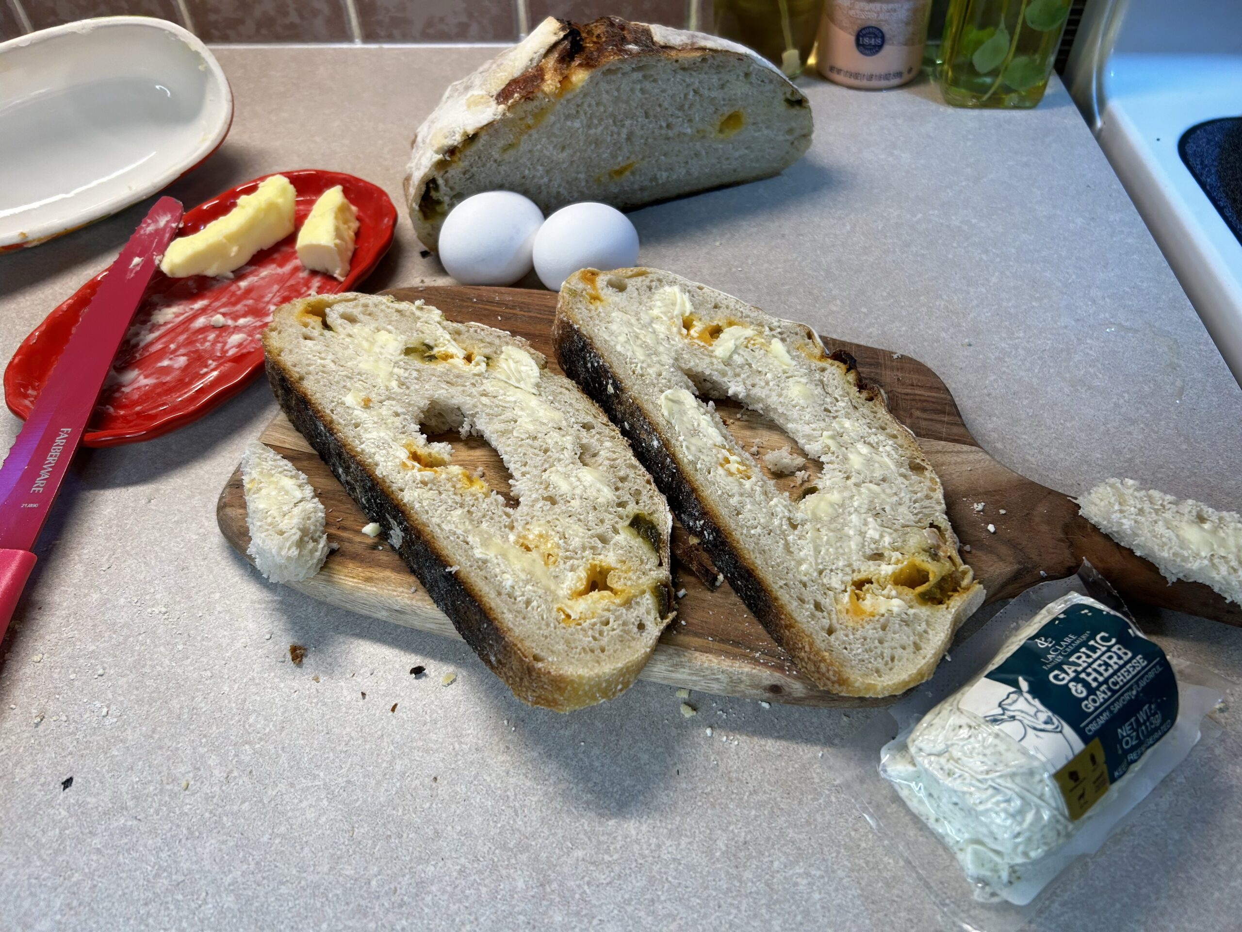 sliced bread, eggs, butter, and goat cheese on counter