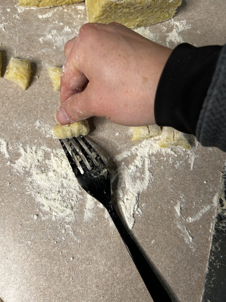 hand rolling potato gnocchi over fork to create ridges