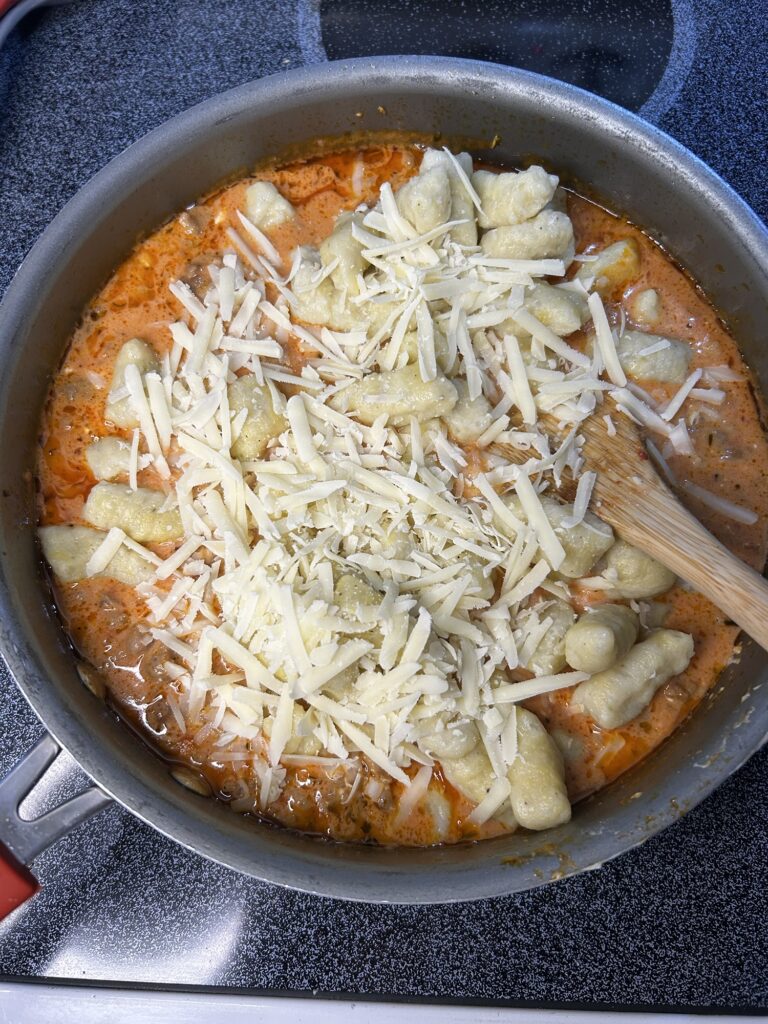pan with homemade potato gnocchi on marinara sauce topped with cheese